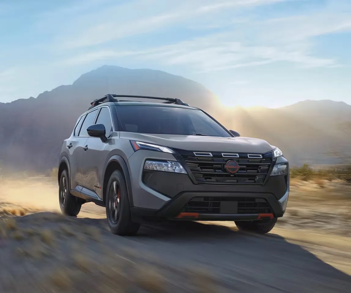 Nissan Rogue 2026 édition Rock Creek roulant sur un sentier de terre en montagne au lever du soleil, démontrant ses capacités tout-terrain et son design audacieux.